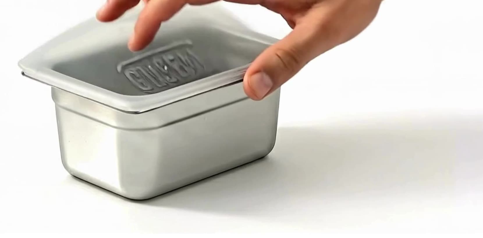 A hand pressing a GNSeal cover onto a gastronorm pan — the same motion as cling film